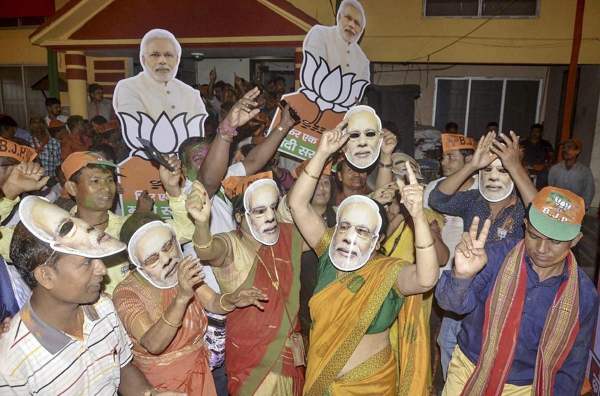 BJP supporters wearing Modi masks celebrate the party's lead in the 2019 Lok Sabha polls, as the counting of votes is in progress, outside the party office in Guwahati on  May 23, 2019. (PTI Photo)