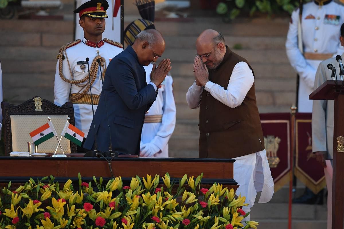 Newly sworn-in cabinet minsiter Amith Shah (R) gestures towards Indian President Ram Nath Kovind after taking the oath of office as cabinet minister at the President house in New Delhi. (AFP Photo)