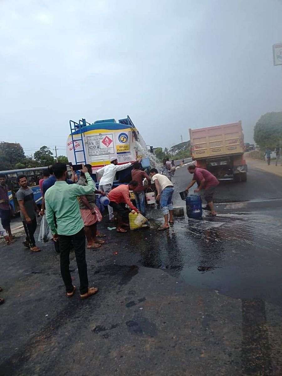 Residents fill containers with diesel spiling out of a tanker on NH-66 in Bhatkal on Monday. dh photo