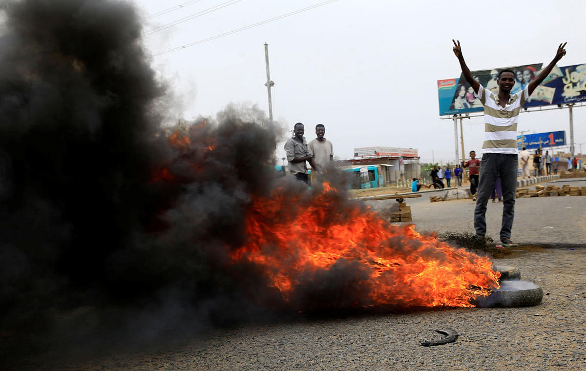 A Sudanese protester gestures near burning tyres used to erect a barricade on a street, demanding that the country's Transitional Military Council handover power to civilians, in Khartoum, Sudan June 4, 2019. REUTERS/Stringer)