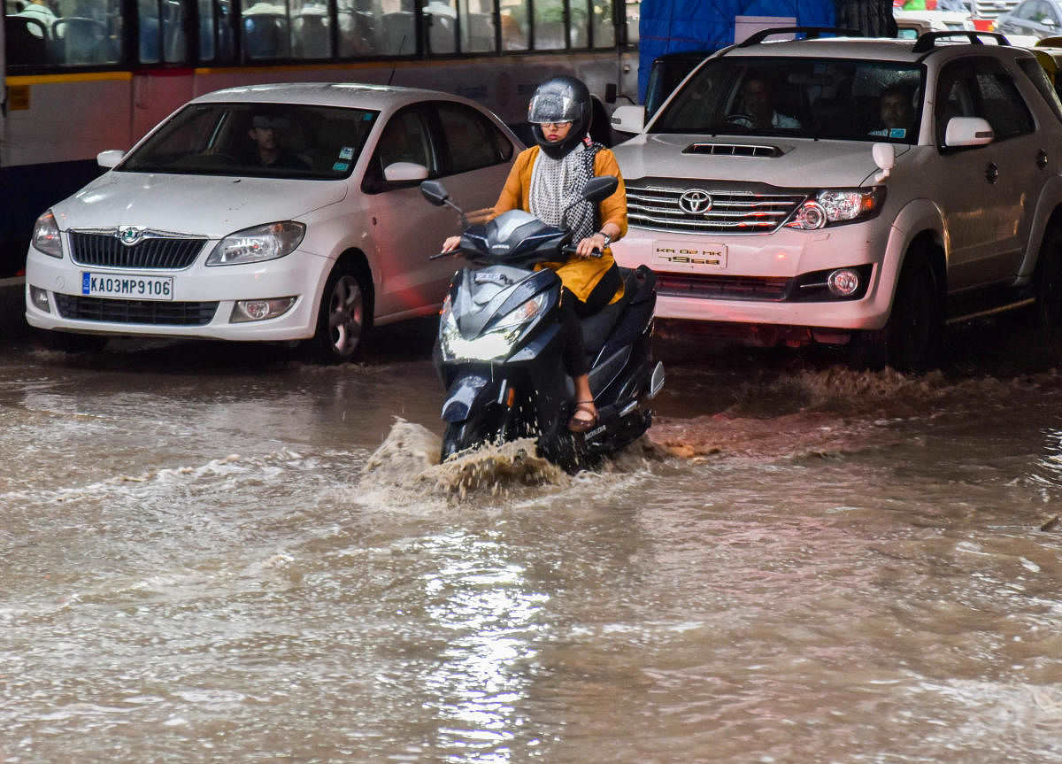 Commuters navigate a waterlogged Okalipuram Road on Wednesday. (DH PHOTO/M S MANJUNATH)
