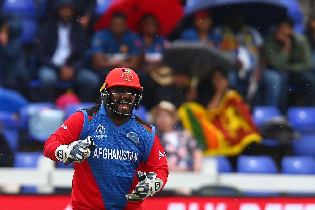 Afghanistan's Mohammad Shahzad celebrates Sri Lanka's Kusal Perera's dismissal for 78 during the 2019 Cricket World Cup group stage match between Afghanistan and Sri Lanka at Sophia Gardens stadium in Cardiff, south Wales, on June 4, 2019. (AFP)