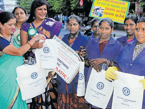 Volunteers distribute cloth bags to civic workers in VV Puram  during an awareness campaign on plastic ban and waste  segregation on Sunday. dh photo