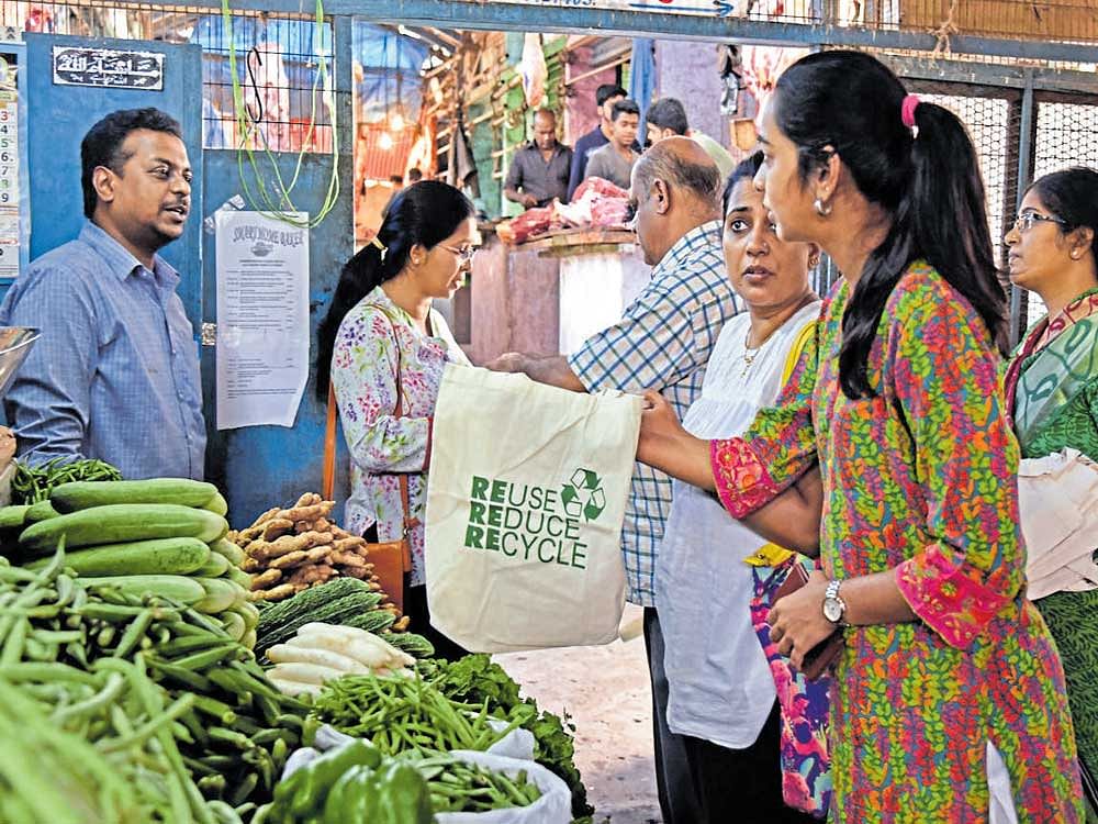 Volunteers of Citizens Welfare Association, Richmond and Langford Town, educate a shopkeeper about the recyclable cloth bags in Johnson Market on Sunday. DH photo