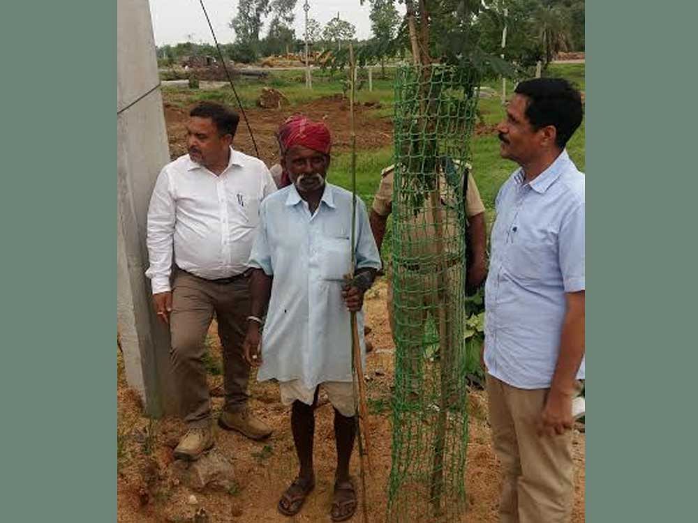 Left to Right) AK Sinha, Chief Conservator of Forests, Watchman and Additional Principle Conservator of Forests RM Dobriyal with a plastic tree guard in Ramayampet. Photo by JBS Umanadh
