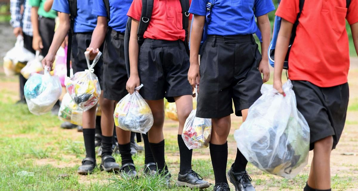 In this photo taken on May 20, 2019, Indian students walk in line holding plastic bags to submit them as school fees at the Akshar Forum school in Pamohi on the outskirts of Guwahati. (AFP)