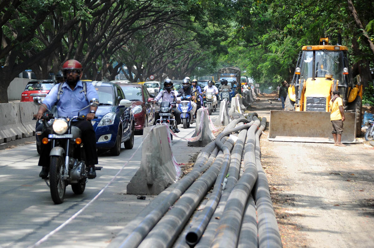 Commuters use a section of the road as white-topping work goes on at CV Raman Road on Saturday. DH Photo/Pushkar V