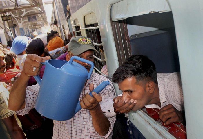 A man offers drinking water to a train passenger at a railway station on a hot day in Patiala on May 28, 2019. PTI