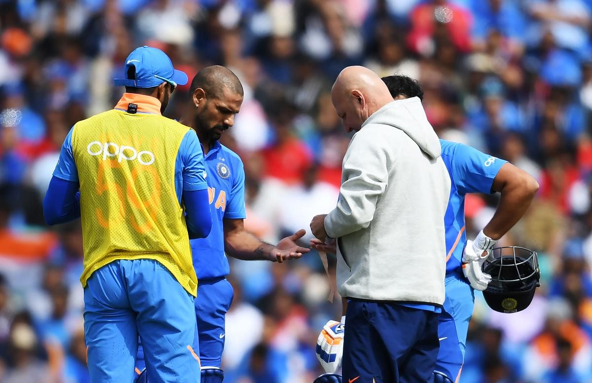 CAUSE FOR WORRY Shikhar Dhawan receives medical treatment after being hit on the hand during India’s game against Australia. AFP