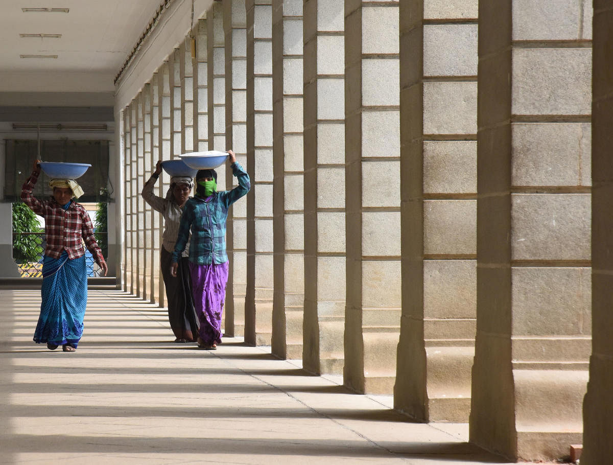 Daily wage labours carry construction materials in Vidhana Soudha, Bengaluru. DH Photo/Janardhan B K