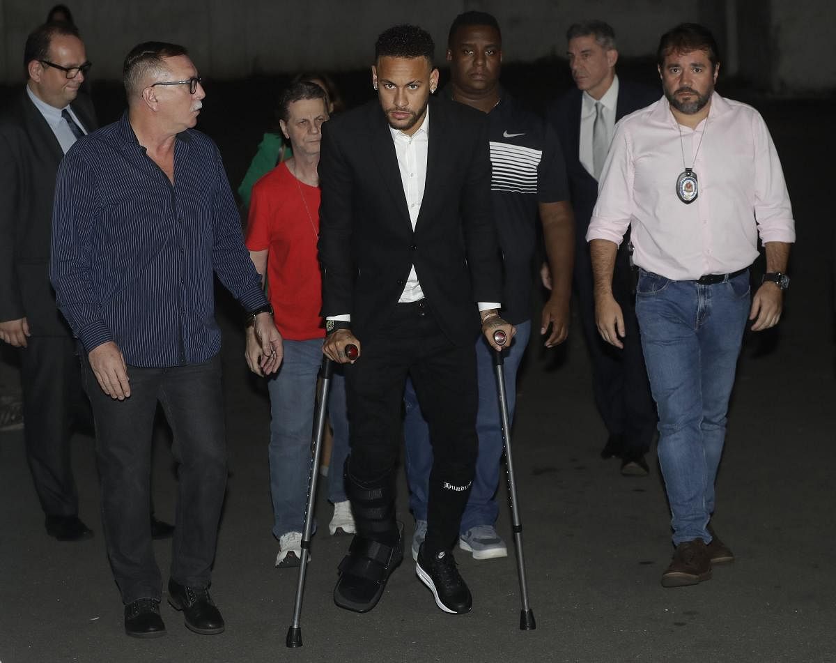 Using crutches because of an injured right ankle, Brazil soccer player Neymar leaves a police station where he answered questions about rape allegations against him in Sao Paulo, Brazil. Credit: AP/PTI
