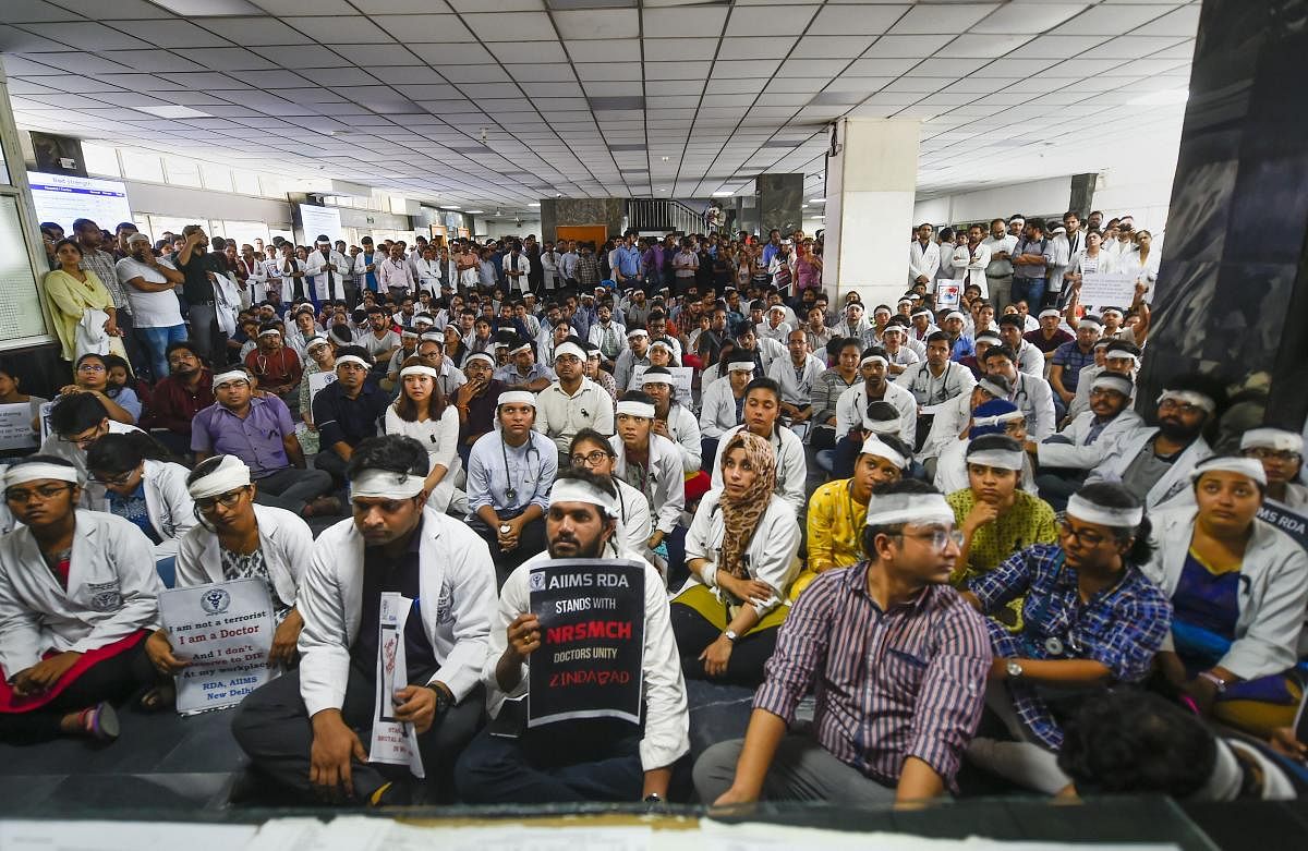 Members of Resident Doctors Association (RDA) of AIIMS wearing bandages on their heads protest to show solidarity with their counterparts in West Bengal, who stopped work on Tuesday protesting against the assault on their colleagues, in New Delhi, Friday,