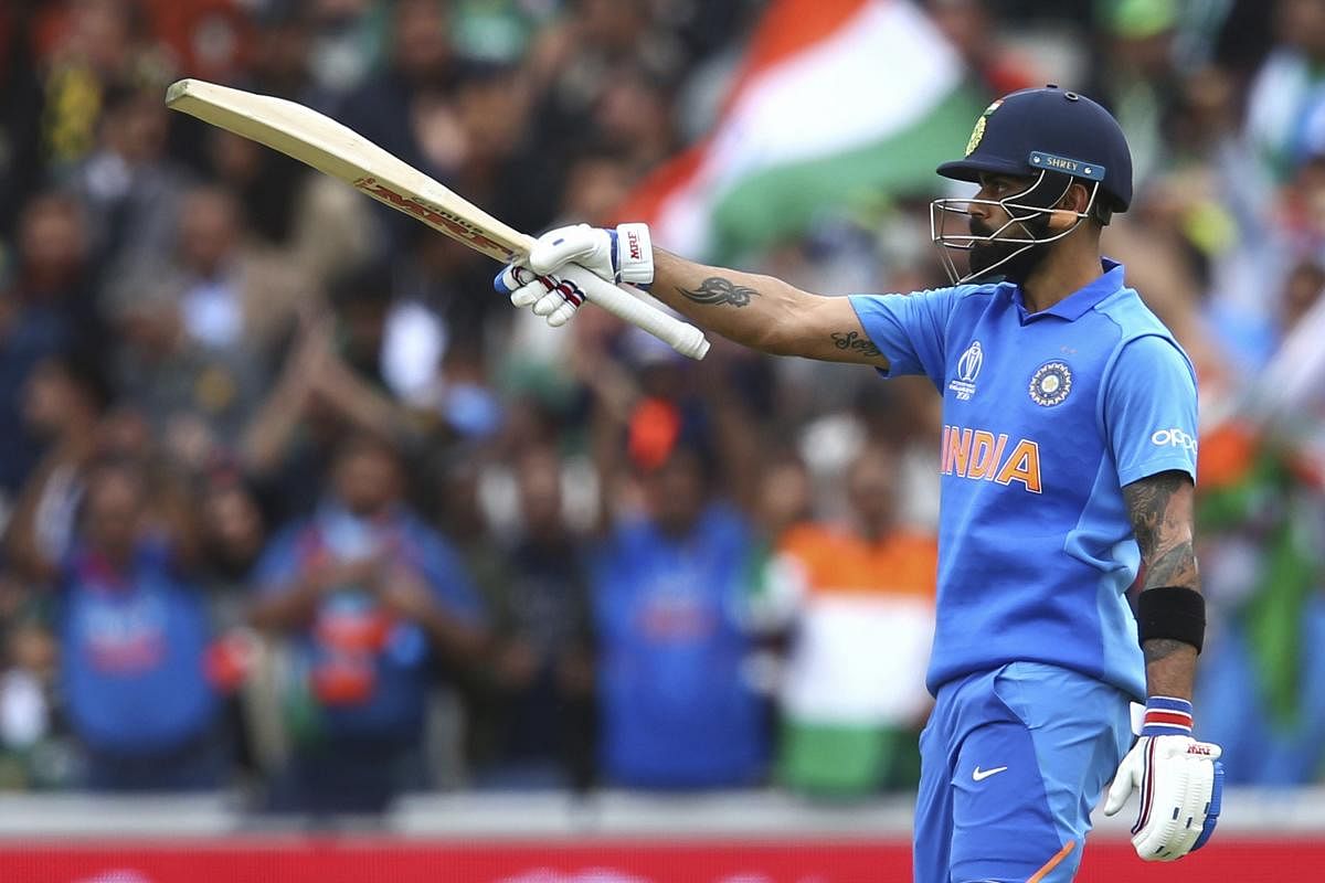 India's captain Virat Kohli raises his bat to celebrates reaching a half-century during the Cricket World Cup match between India and Pakistan at Old Trafford in Manchester, England on Sunday. AP/PTI photo