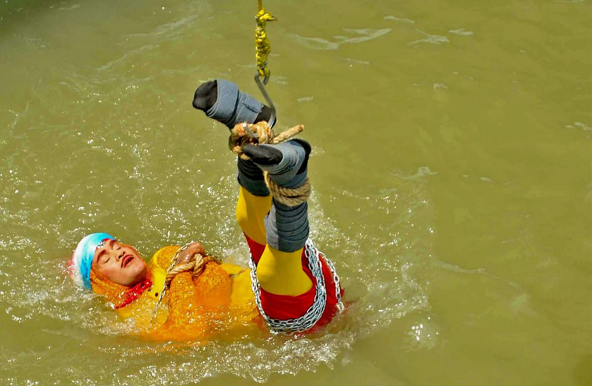 n this photo taken on June 16, 2019 Indian stuntman Chanchal Lahiri, known by his stage name "Jadugar Mandrake", is lowered into the Ganges river, while tied up with steel chains and ropes, in Kolkata. - An Indian magician who went missing after being lowered into a river tied up in chains and ropes in a Houdini-inspired stunt is feared drowned, police said June 17. (AFP)