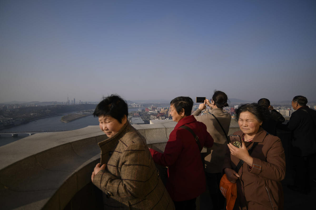 Tourists from China stand on a viewing deck of the Juche tower overlooking the city skyline of Pyongyang. (AFP File Photo)