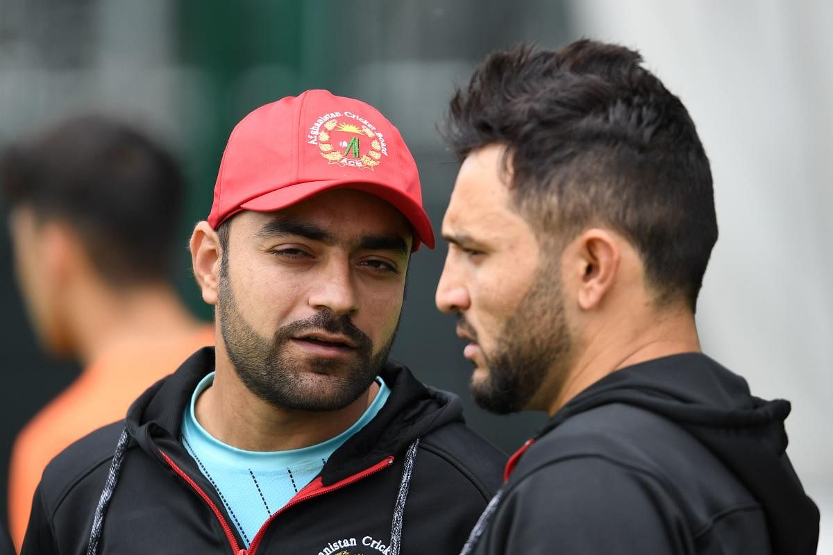 Afghanistan's Rashid Khan talks with Afghanistan's captain Gulbadin Naib. (AFP)