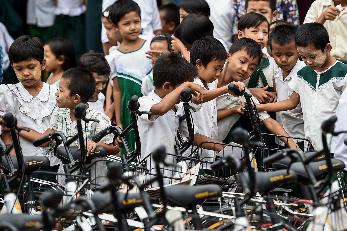 In this picture taken on June 18, 2019, students look at bicycles, previously used in bike-sharing companies and shipped from Singapore, which have been donated as part of the "Lesswalk" scheme at a school on the outskirts of Yangon. (Photo by Ye Aung THU