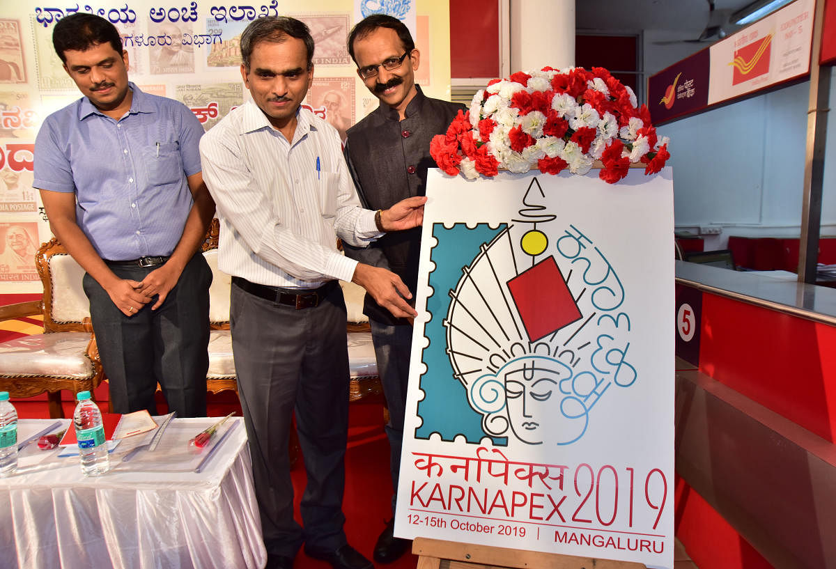 Karnataka Circle Chief Post Master General (CPMG) Dr Charles Lobo unveils the logo of ‘KARNAPEX 2019’ (Karnataka Philatelic Exhibition) at the head post office in Pandeshwar, Mangaluru, on Thursday.