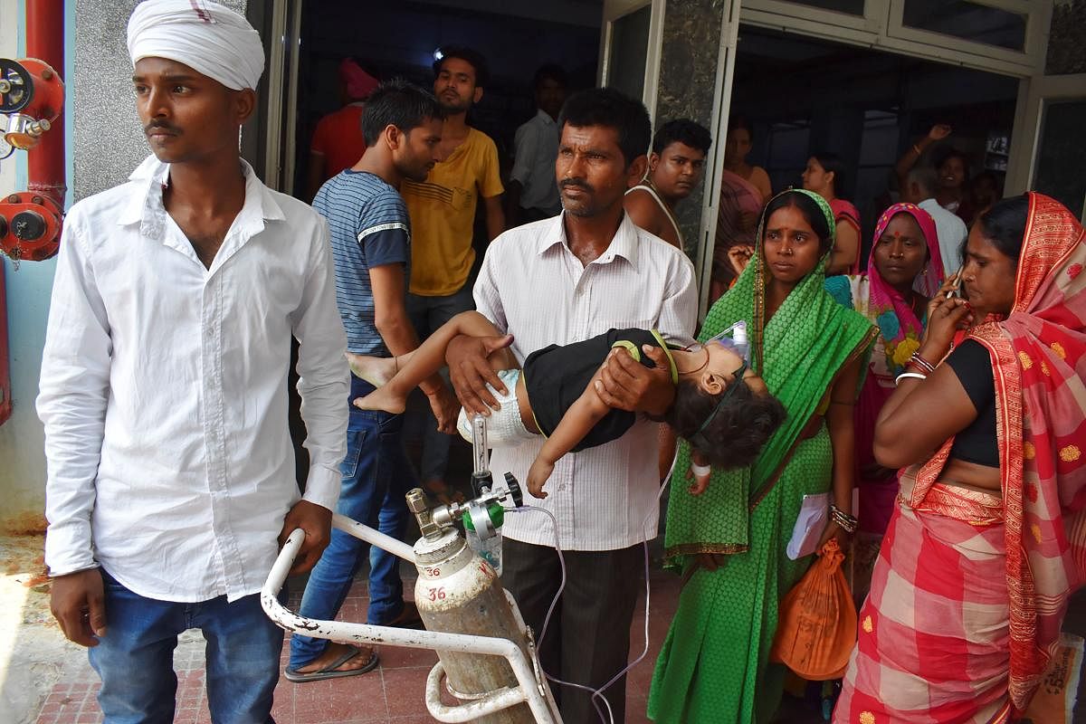The father (C) of four-year-old kid stands outside Kejriwal hospital along with relatives while holding his son, who is suffering from AES, in Muzaffarpur, Bihar. (AFP)
