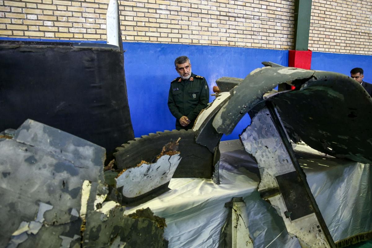 General Amir Ali Hajizadeh (C), Iran's Head of the Revolutionary Guard's aerospace division, looks at debris from a downed US drone reportedly recovered within Iran's territorial waters and put on display by the Revolutionary Guard in the capital Tehran o