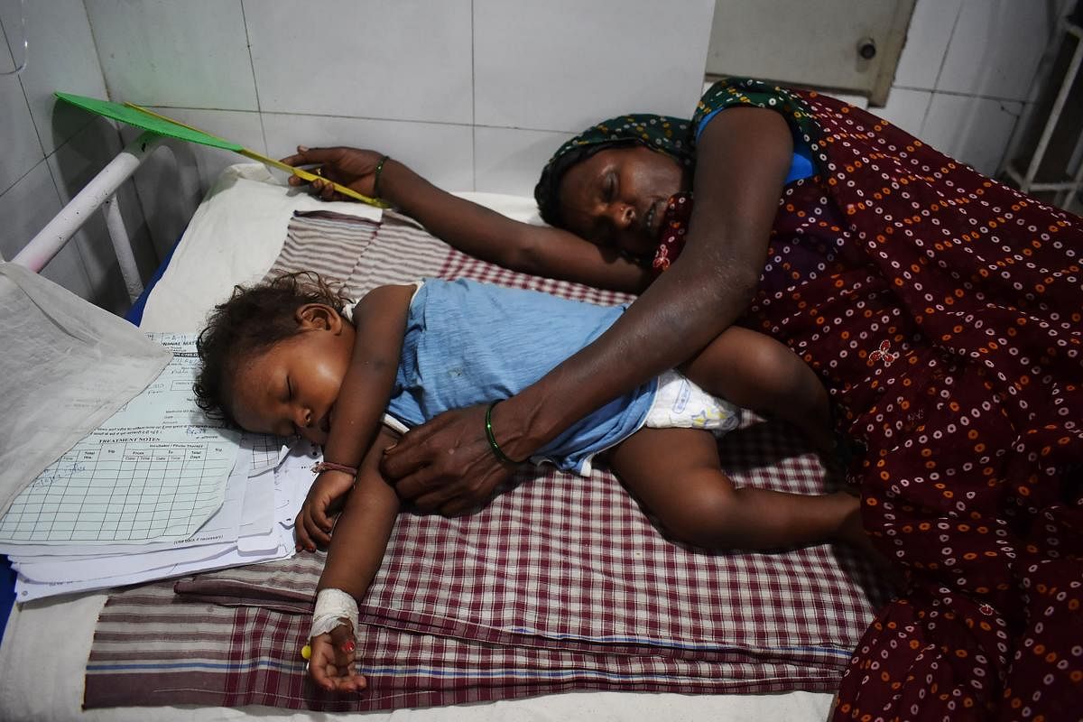 In this picture taken on June 20, 2019, an Indian mother (R) lays next to her child who is suffering from Acute Encephalitis Syndrome (AES), at Kejriwal hospital in Muzaffarpur in the Indian state of Bihar. (Photo by STR / AFP)