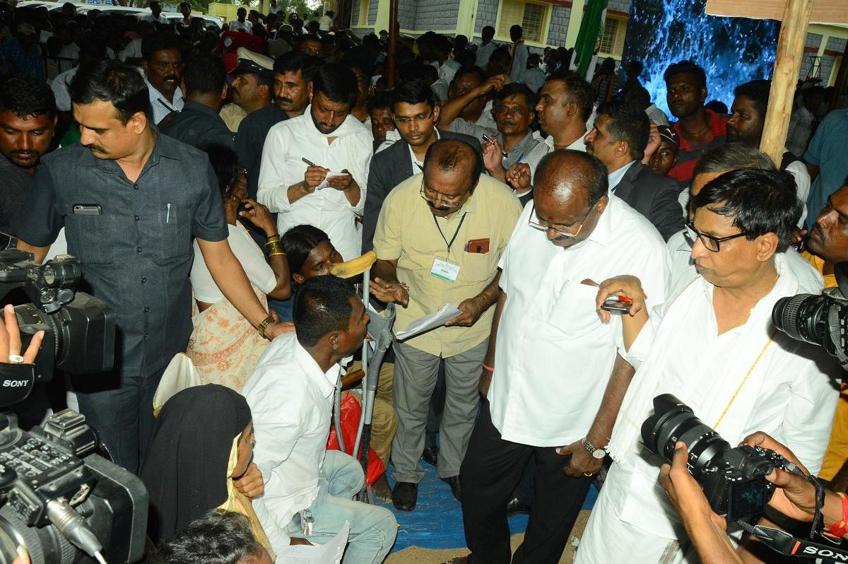 Chief Minister H D Kumaraswamy interacts with a specially abled person during his grama vastayva at Chandaraki village in Yadgir taluk. DH File Photo