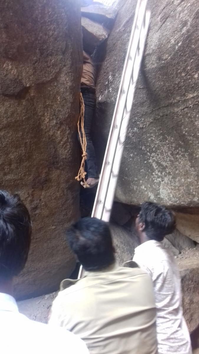 Police and firefighters conduct operations to rescue a man trapped in a narrow opening between the boulders in Hampi on Monday.