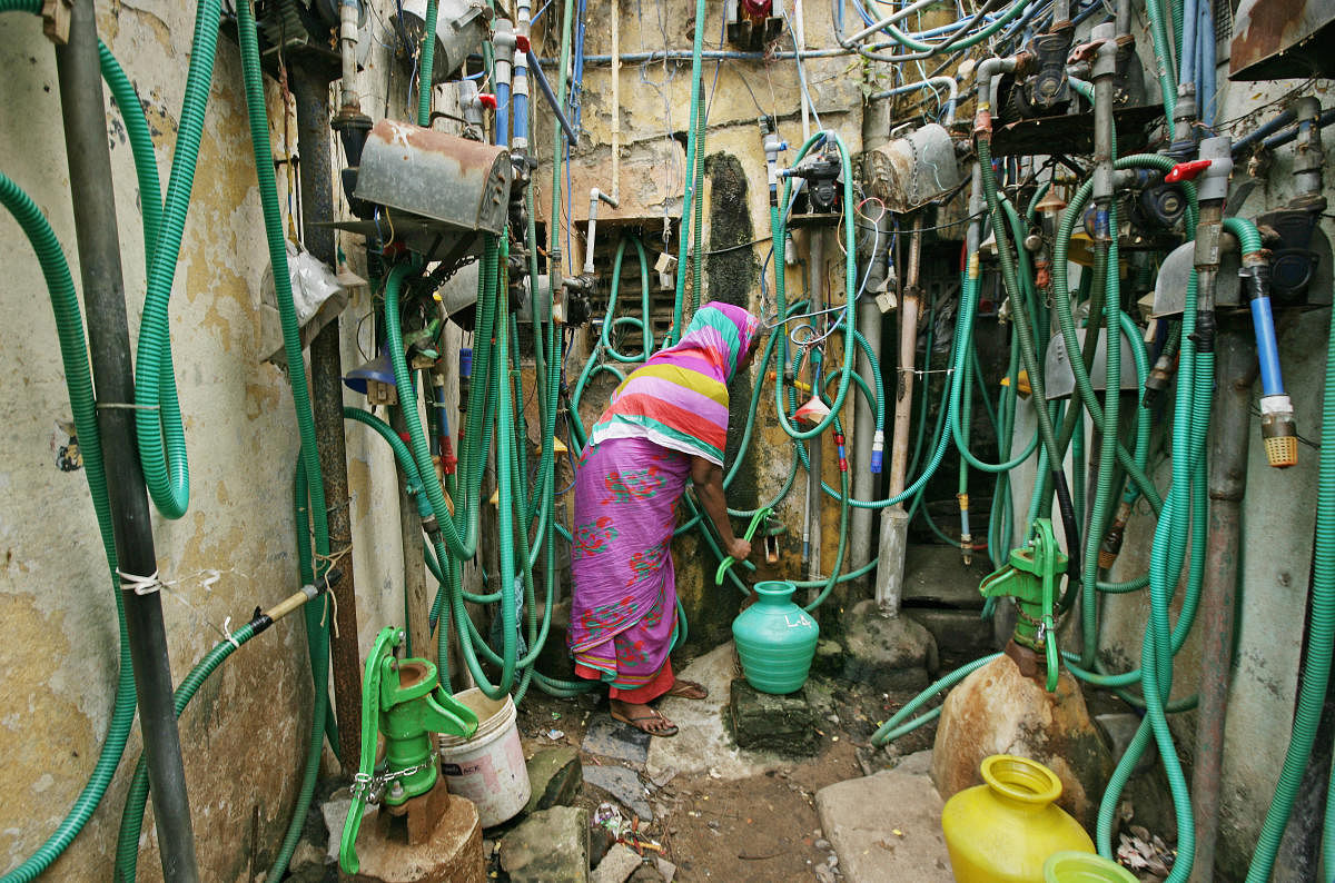 A woman uses a hand pump to fill up a container with drinking water in Chennai. REUTERS