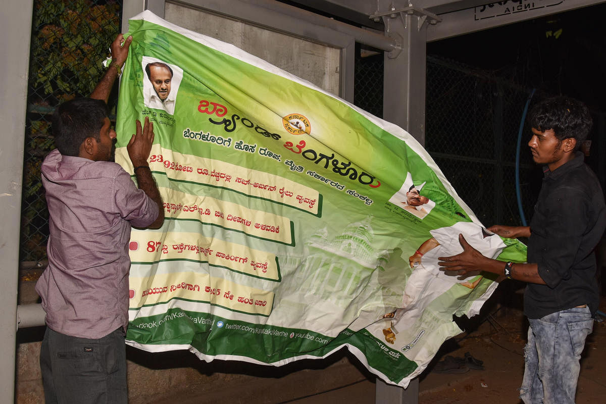 BBMP workers remove flexes trumpeting government's achievements at Vasanthnagar in Bengaluru. DH File Photo