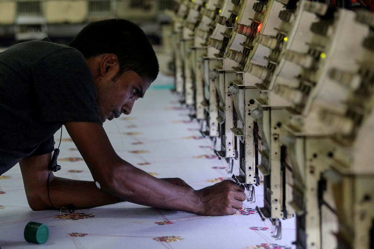 A worker adjusts the thread on an embroidery machine at a workshop in Mumbai. REUTERS