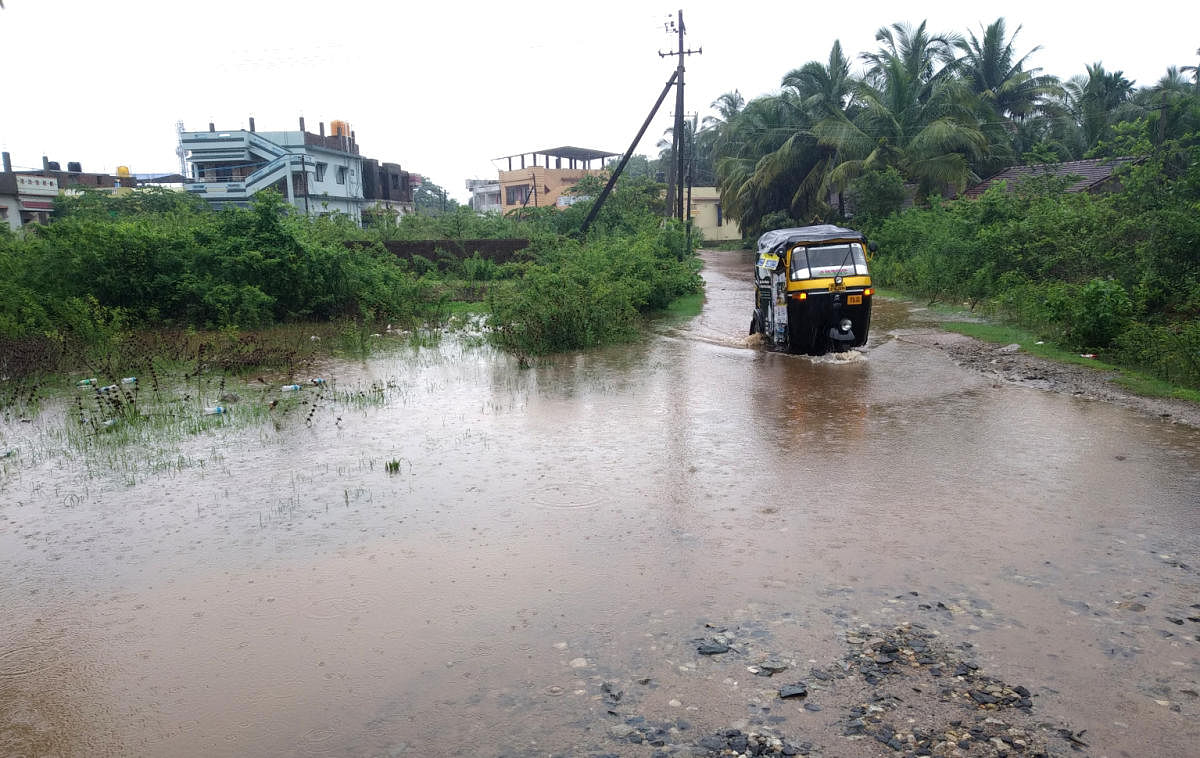 An auto rickshaw wades through a flooded road in Karwar following heavy rainfall that lashed Uttara Kannada district on Thursday. DH Photo