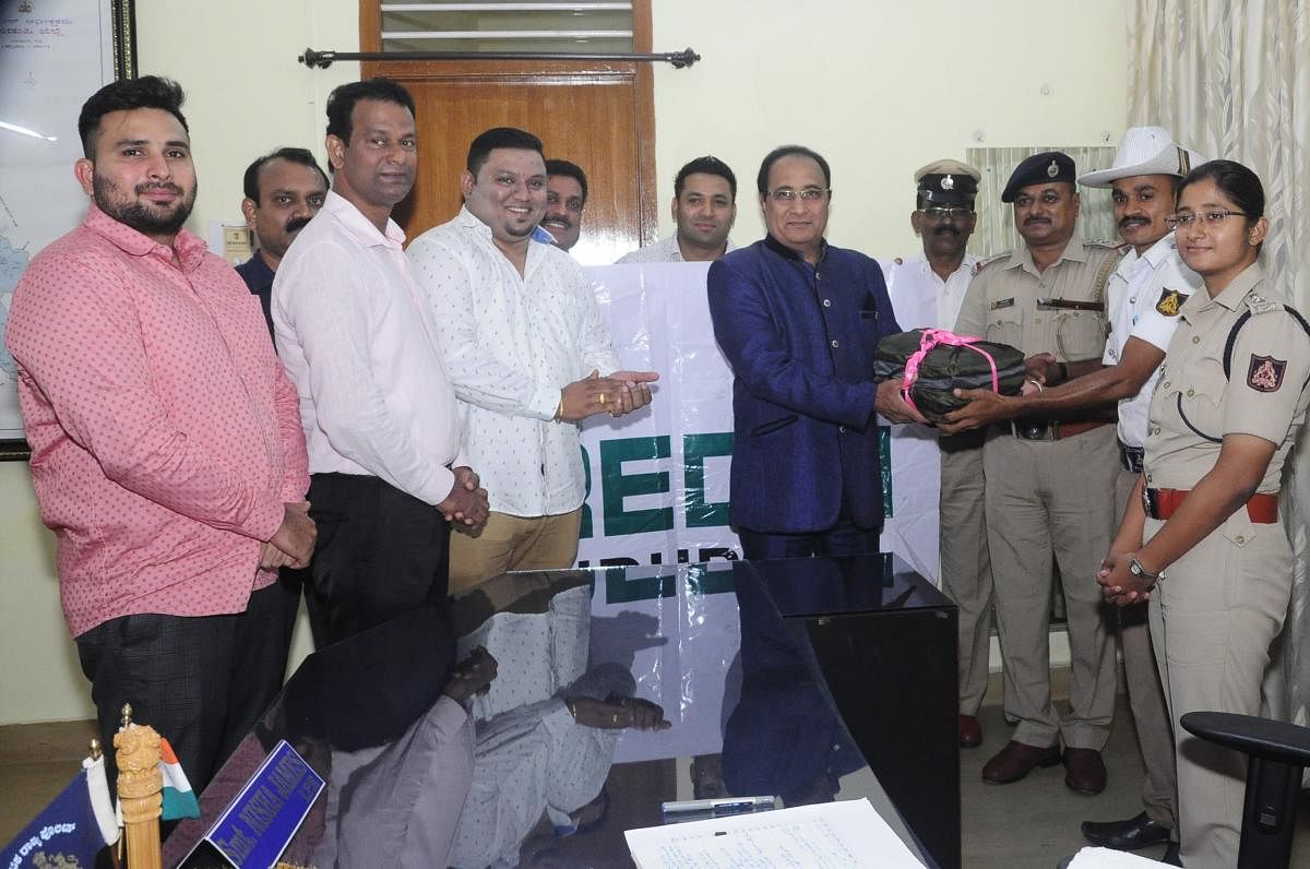 Credai District President Jerry Vincent Dias hands over raincoats to traffic police personnel in Udupi on Friday.