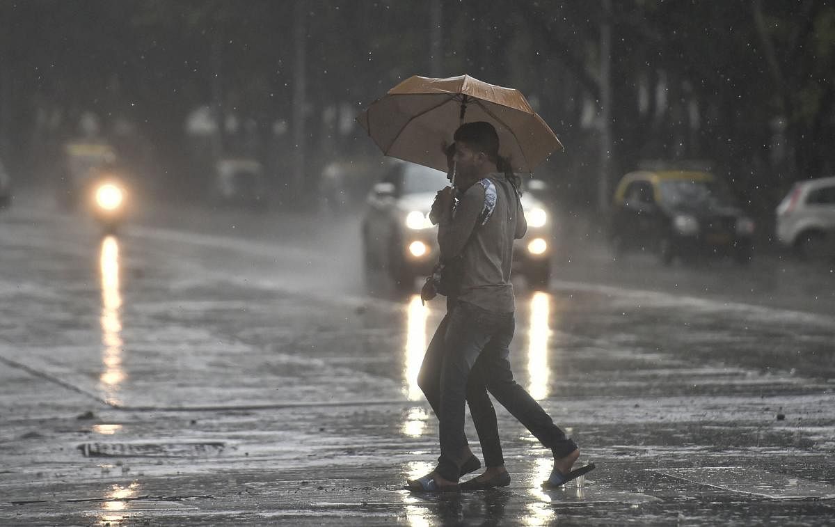 Pedestrians walk across a road during monsoon rain in Mumbai. (PTI Photo)