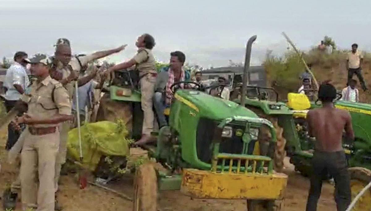 Chole Anitha, a female forest officer, climbs on a tractor to save herself from the brutal attack of the farmers, who were protesting against the ploughing of land by the forest department for a mass plantation programme, at Sarsala village in Kaghaznagar.