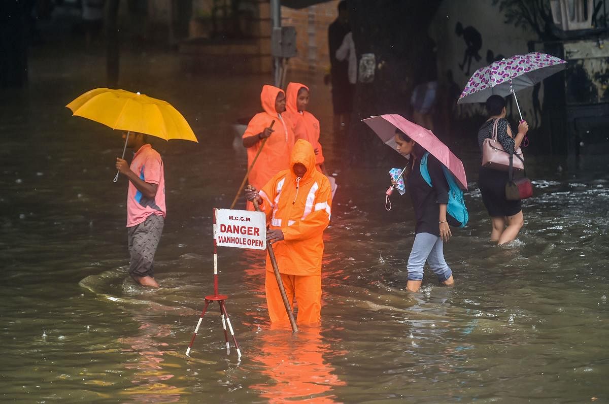 Mumbai: A Municipal worker stands guard to warn pedestrians of an open manhole on a waterlogged street following heavy monsoon rains, in Mumbai, Monday, July 01, 2019. (PTI Photo/Mitesh Bhuvad)(PTI7_1_2019_000087B)