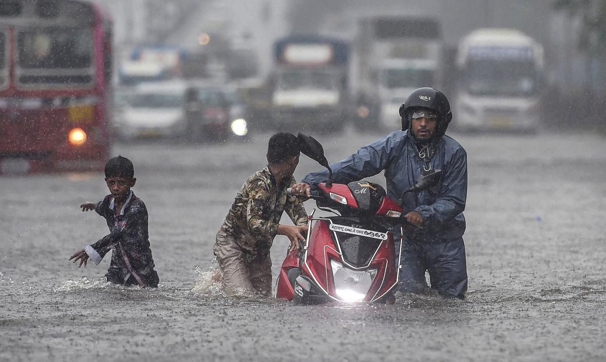 People wade through a waterlogged street after heavy rain lashed Mumbai on Tuesday. PTI