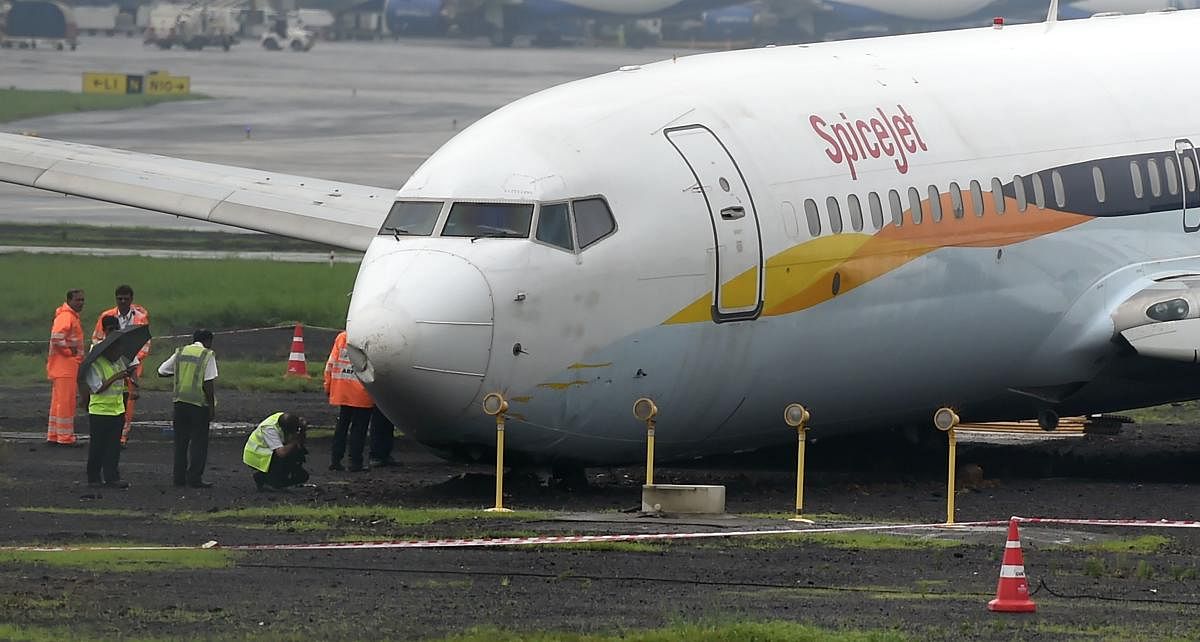 A SpiceJet aircraft is surrounded by airport staff as it stands stranded off the tarmac at Chhatrapati Shivaji Maharaj International Airport in Mumbai on July 2, 2019, after it overran the runway while landing during heavy rain, causing no injuries. AFP p