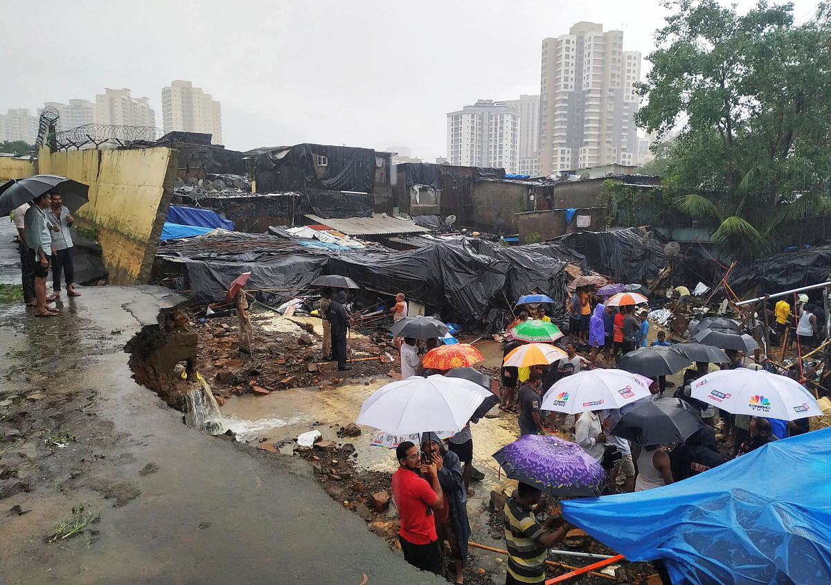 People stand among the debris after a wall collpased on hutments due to heavy rains in Mumbai, India July 2, 2019. REUTERS