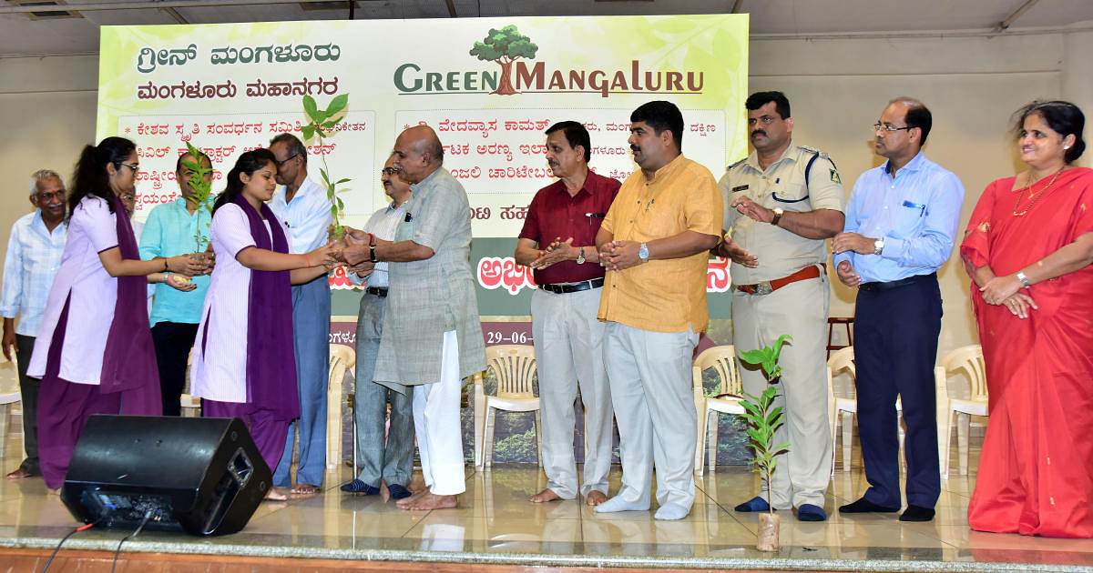 Dr Vaman Shenoy, president of the Green Mangaluru Programme, gives a sapling to a student during the launch of the programme in Mangaluru.