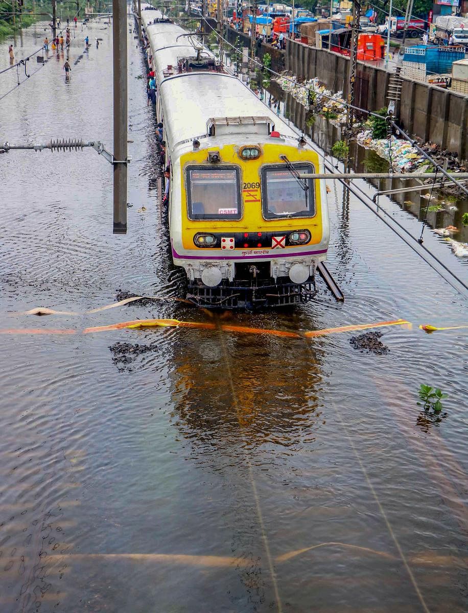 A suburban local train moves across submerged railway tracks following heavy monsoon rains, in Mumbai. (PTI Photo)