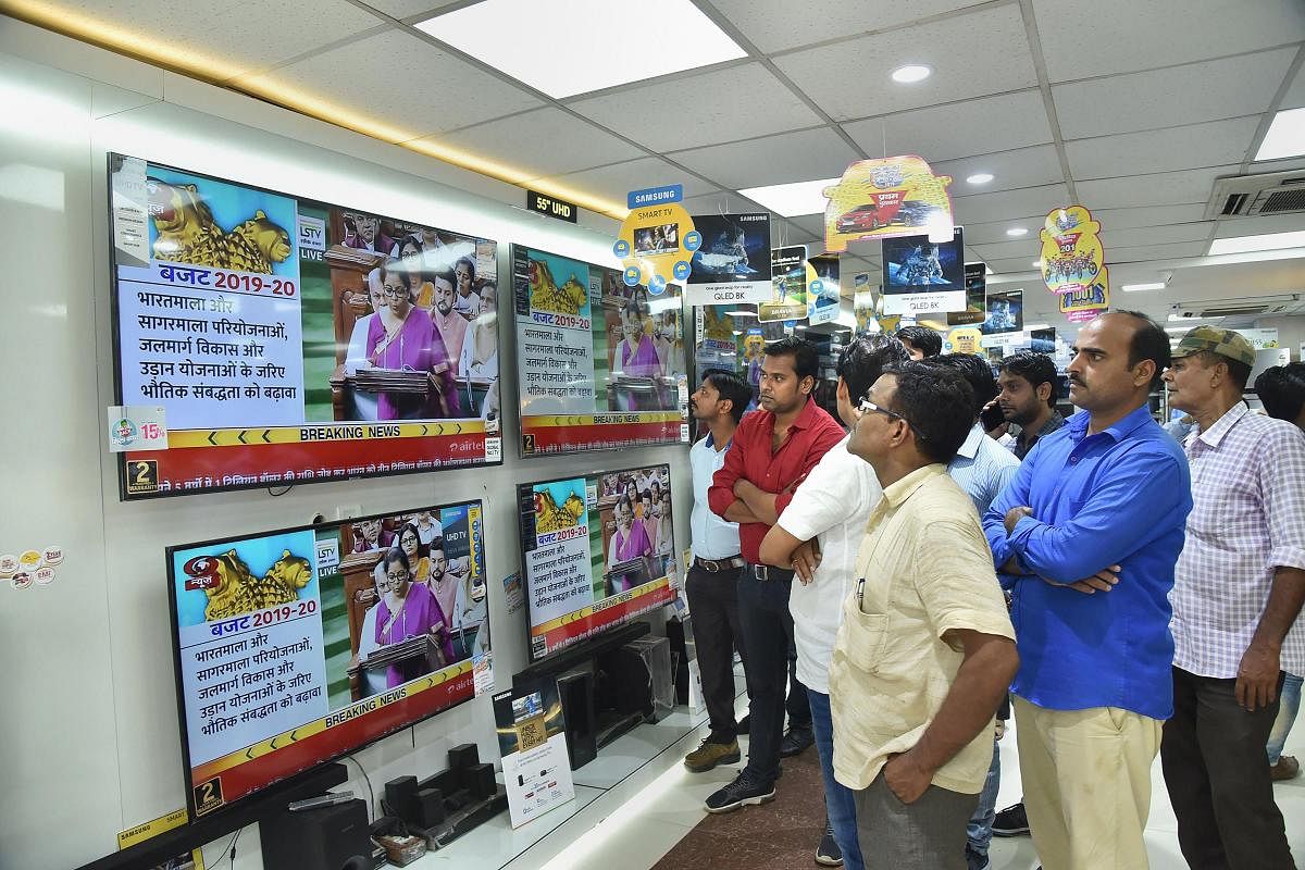 People watch Finance Minister Nirmala Sitharaman tabling the Union Budget 2019-20, on TV sets at a showroom in Patna. (PTI Photo)
