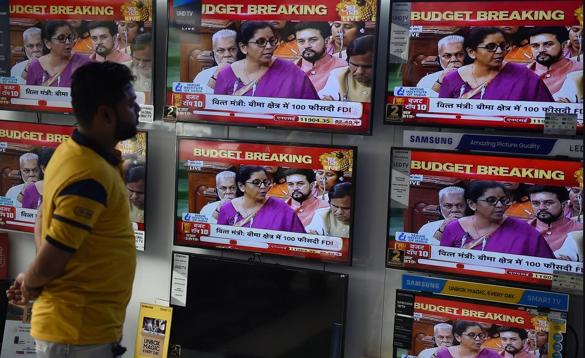 A salesman watches Indian Finance Minister Nirmala Sitharaman delivering her budget speech on television screens at an electronics store in New Delhi on July 5, 2019. (AFP)