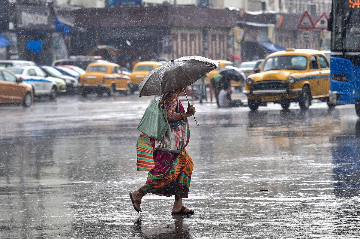 A pedestrian rushes to cross a busy city street during pre-monsoon rainfall, in Kolkata. PTI file photo