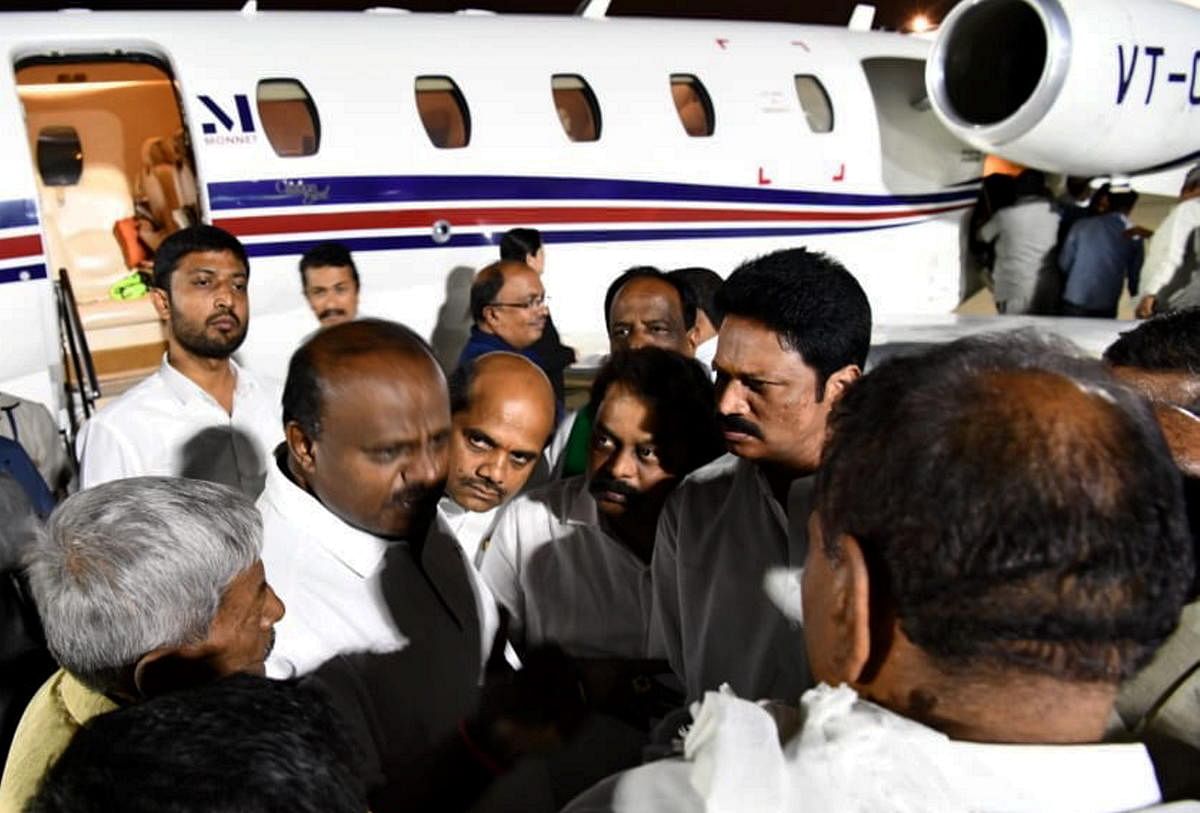 Karnataka CM H D Kumaraswamy talks with party MLA's and Ministers at the HAL airport, Bengaluru after his 10 day personal trip to US (PTI Photo)