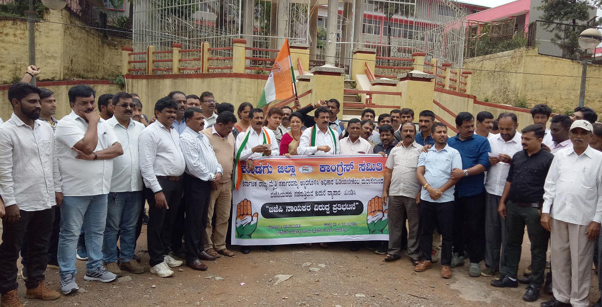 Congress leaders stage a protest against BJP in front of Gandhi Mantapa in Madikeri.