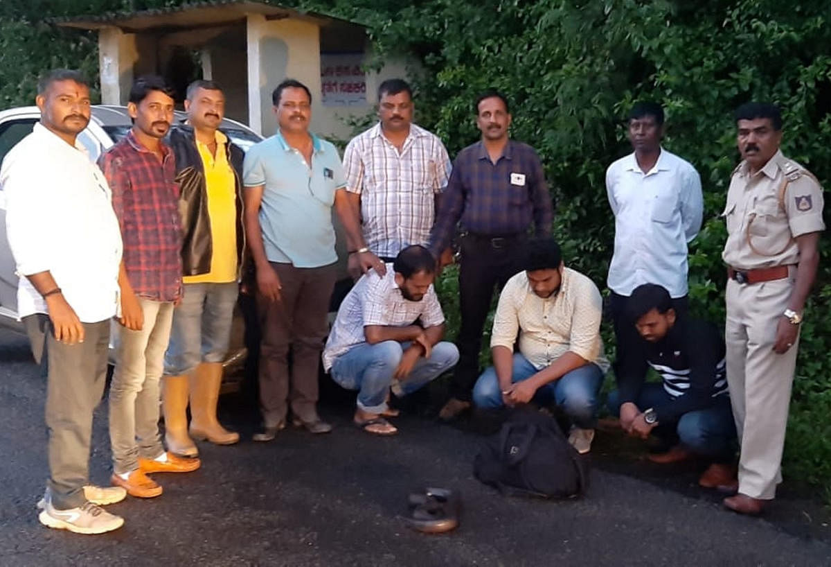 The accused (sitting) with the seized sand boa. The members of the Forest Department team (standing) which nabbed the accused are also seen.
