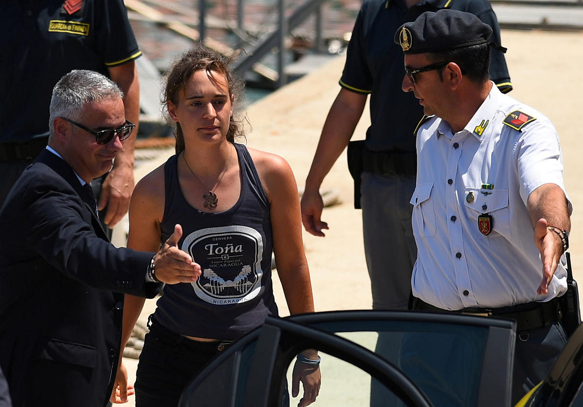 Carola Rackete, the 31-year-old Sea-Watch 3 captain, disembarks from a Finance police boat and is escorted to a car, in Porto Empedocle, Italy on July 1, 2019. (REUTERS File Photo)