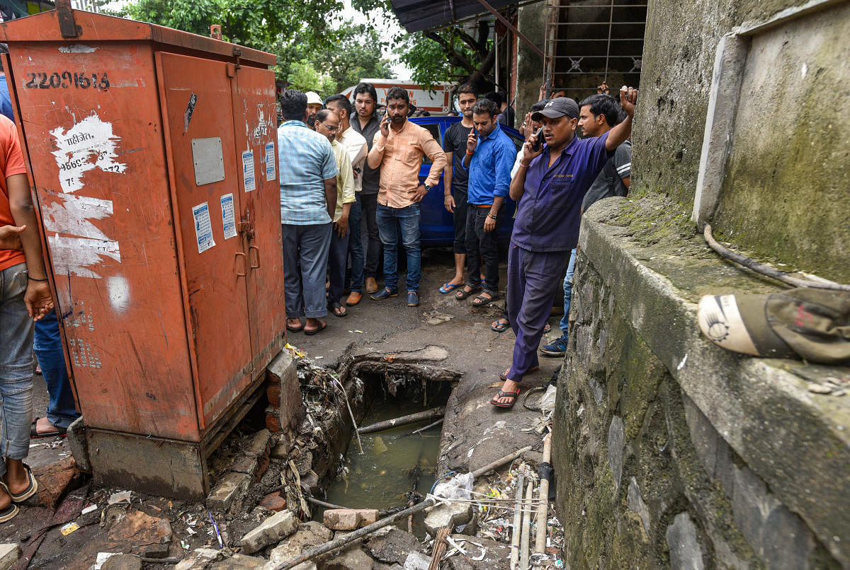 People stand near a gutter into which a baby fell, at Goregaon East in Mumbai. PTI photo