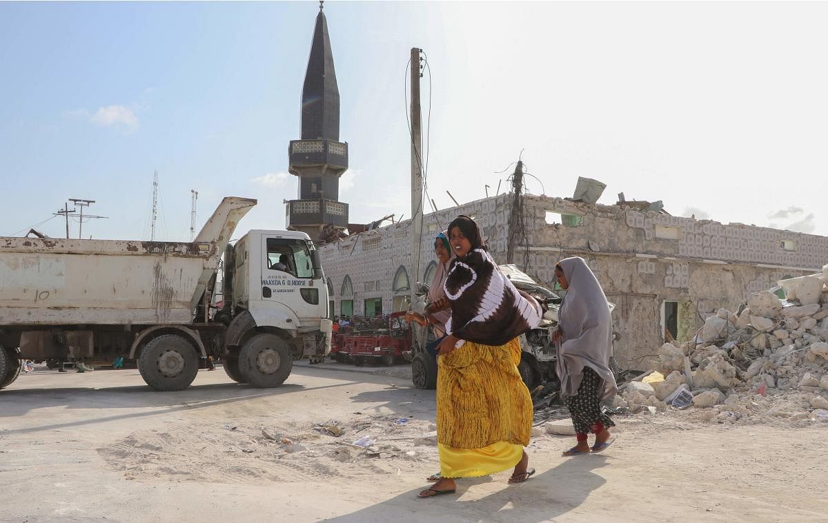 Women walk past the site of car bomb attack near Somali parliament in Mogadishu on June 15, 2019. - A car bomb exploded near the Somali parliament on June 15, 2019, killing eight people, emergency workers said, hours after militia executed nine civilians