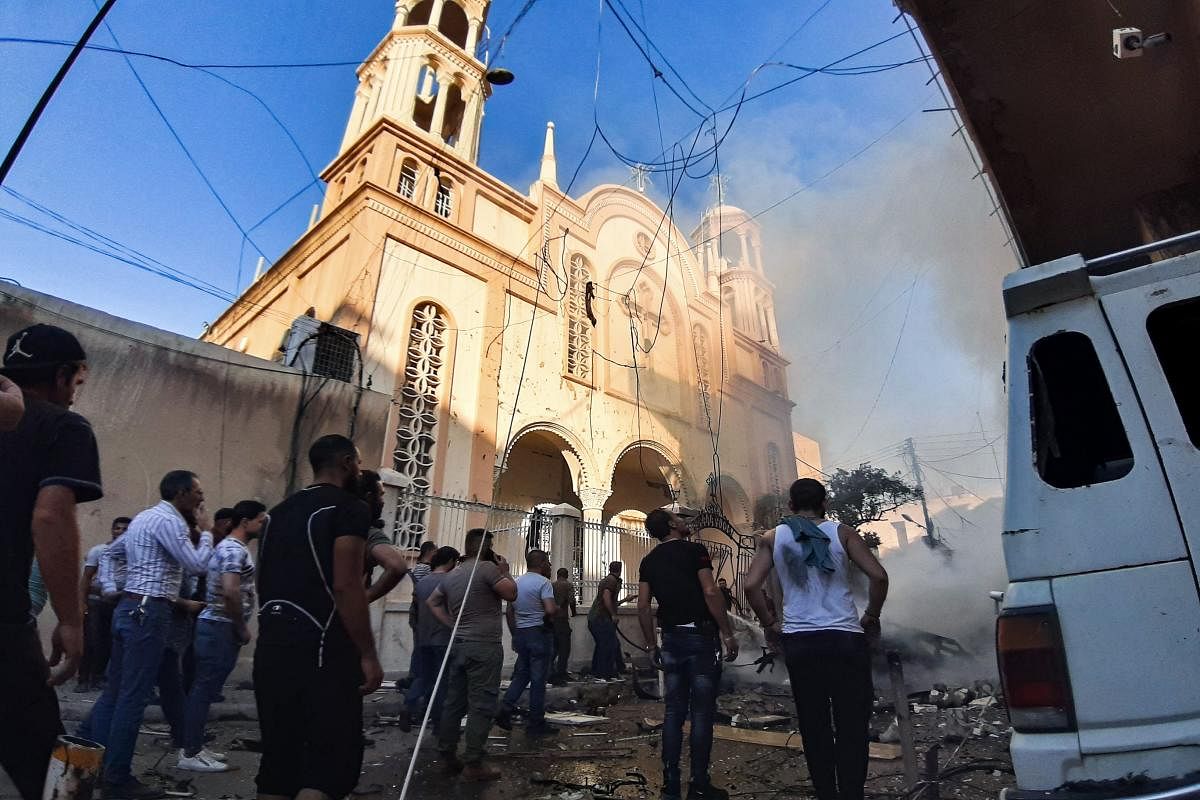 TOPSHOT - People gather at the scene of a car bomb explosion outside a church in the Kurdish-majority city of Qamishli in northeast Syria on July 11, 2019. - There was no immediate claim for the attack, which Syrian state television said left several peop